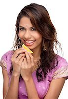 deepavali sweet - A young woman smiles at the camera as she eats a slice of - 655-01781327er
