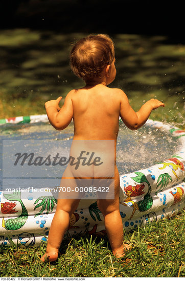 Back View of Nude Child Standing By Inflatable Swimming Pool