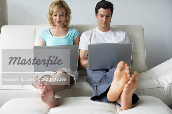 2 computers brunette foot woman comfortable couple on couo computer two