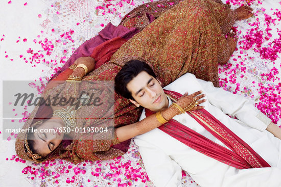 High angle view of a newlywed couple in traditional wedding outfits sleeping