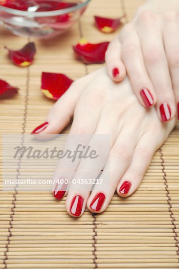 Beautiful hand with perfect nail red manicure and rose petals