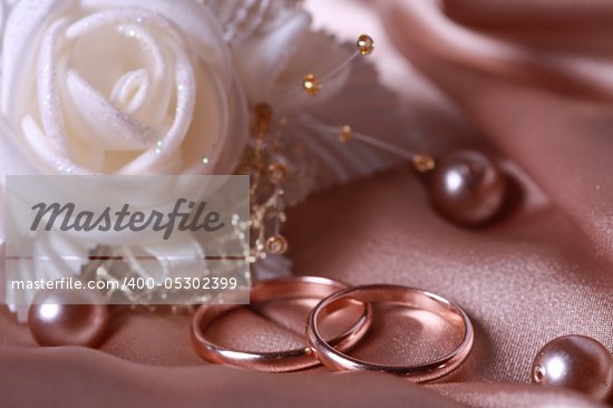 Wedding rings with satin rose on silk background