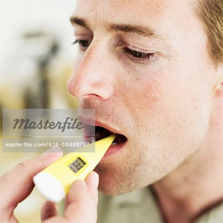 Close-up of a <b>human hand</b> inserting a digital thermometer into a man&#39;s mouth - 618-00488757em-Close-up-of-a-human-hand-inserting-a-digital-thermometer-into-a