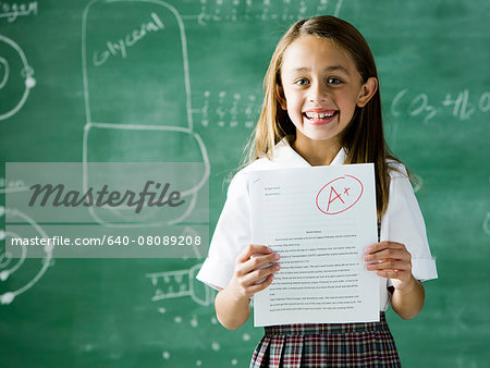 640-08089208em-girl-in-a-classroom-standing-in-front-of-a-chalkboard-with-an-a-plus-paper.jpg