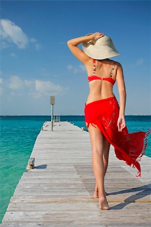 simsearch:400-03950469,k - One of a large series. Woman in red bikini walking down a tropical jetty Stock Photo - Budget Royalty-Free & Subscription, Code: 400-04018253