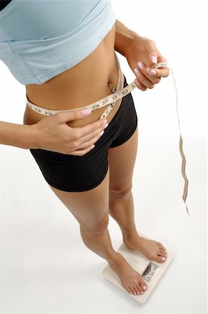 simsearch:400-07219376,k - A tanned slim young woman measuring her waistline while standing on a scale. Focus on tape measure and waist. Stock Photo - Budget Royalty-Free & Subscription, Code: 400-04029171