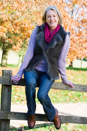 simsearch:400-04035087,k - Senior woman sitting on fence with autumn trees in background Stock Photo - Budget Royalty-Free & Subscription, Code: 400-04035045
