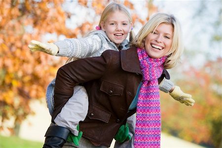 simsearch:400-04035087,k - Mother giving daughter piggyback ride in autumn woodland Stock Photo - Budget Royalty-Free & Subscription, Code: 400-04035084