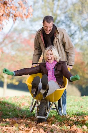 simsearch:400-04035087,k - Man pushing wife through autumn leaves in wheelbarrow Stock Photo - Budget Royalty-Free & Subscription, Code: 400-04035082