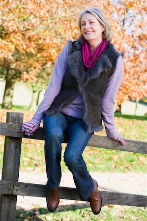 simsearch:400-04035087,k - Senior woman sitting on fence with autumn woodland behind Stock Photo - Budget Royalty-Free & Subscription, Code: 400-04035128