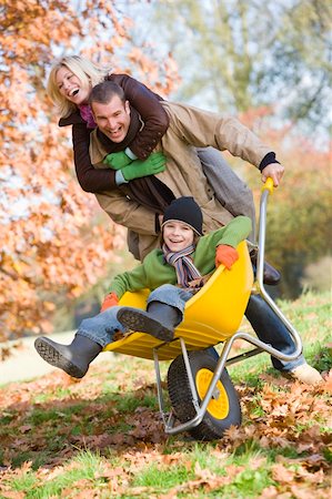 simsearch:400-04035087,k - Father and mother pushing son in wheelbarrow through autumn leaves Stock Photo - Budget Royalty-Free & Subscription, Code: 400-04035134