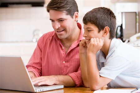 simsearch:400-05751173,k - Man helping young boy in kitchen with laptop smiling Stock Photo - Budget Royalty-Free & Subscription, Code: 400-04044124