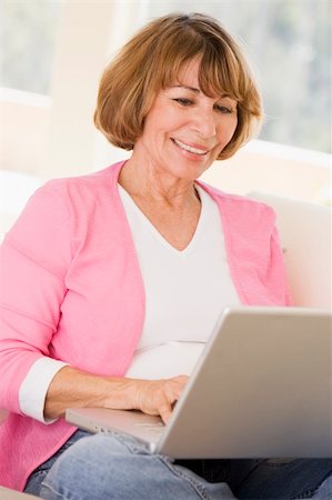 Woman in living room with laptop smiling Stock Photo - Budget Royalty-Free & Subscription, Code: 400-04046314