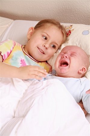 Cute older sister with crying newborn in bed Stock Photo - Budget Royalty-Free & Subscription, Code: 400-04055597