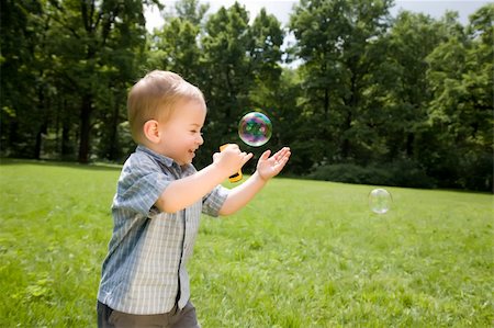 simsearch:400-04638236,k - Little Boy Catch Soap Bubbles On The Green Grass Photographie de stock - Aubaine LD & Abonnement, Code: 400-04069253