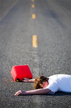 out of gas - teen with empty gas can lies dead in the middle of the road Stock Photo - Budget Royalty-Free & Subscription, Code: 400-04060353