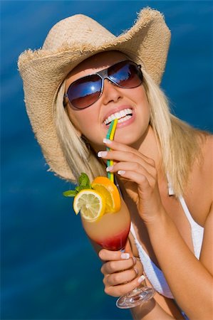 simsearch:6109-06004195,k - A beautiful blond haired model wearing a white bikini laughing and drinking a cocktail in front of a beautiful blue sea Stock Photo - Budget Royalty-Free & Subscription, Code: 400-04060394
