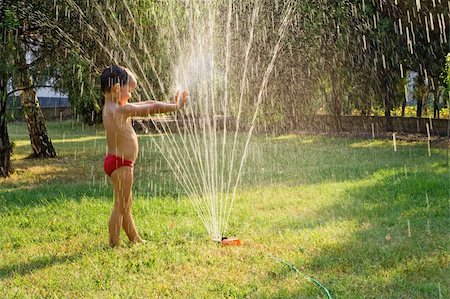 Young boy having fun playing with water from a sprinkler in the garden Stock Photo - Budget Royalty-Free & Subscription, Code: 400-04061080