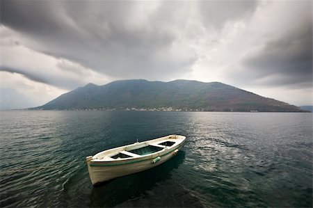 A boat tied with a rope. Storm beginning, dark clouds above, strong wind, a distant misty island on the background. Stock Photo - Budget Royalty-Free & Subscription, Code: 400-04097544