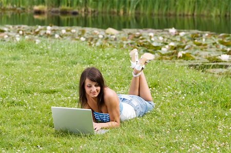 simsearch:400-04416781,k - cute brunette in casual dress standing alone on the grass and working on the computer Stock Photo - Budget Royalty-Free & Subscription, Code: 400-04092813