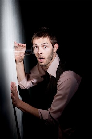 Handsome young man using glass against wall to eavesdrop Stock Photo - Budget Royalty-Free & Subscription, Code: 400-04114764