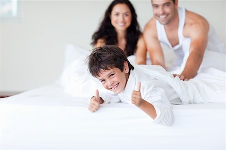 Happy family together on bed with thumbs up Foto de stock - Super Valor sin royalties y Suscripción, Código: 400-04116371