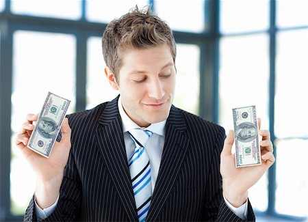 simsearch:400-05715208,k - Young businessman holding dollars in office Stock Photo - Budget Royalty-Free & Subscription, Code: 400-04118207