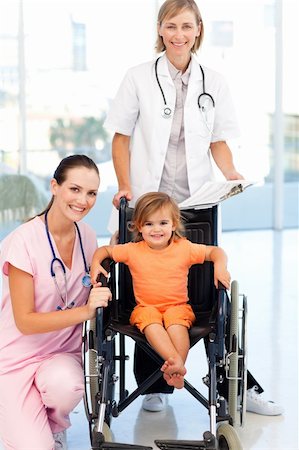 Little girl in a wheelchair with attractive doctors looking at the camera Stock Photo - Budget Royalty-Free & Subscription, Code: 400-04118493