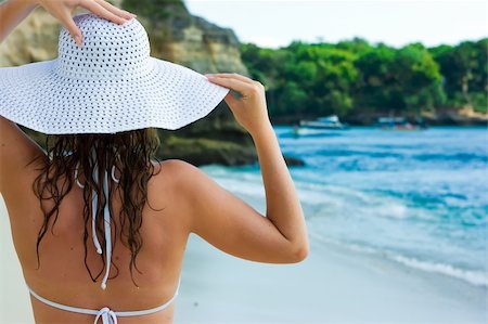 simsearch:400-04127648,k - Belle brune aux cheveux longs en chapeau blanc se dresse sur la plage de sable de l'océan sur Bali en Indonésie Photographie de stock - Aubaine LD & Abonnement, Code: 400-04127672