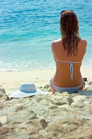 simsearch:400-04127663,k - Beautiful brunette with long hair in white hat and swimsuit sits on the sand ocean beach on Bali in Indonesia Foto de stock - Super Valor sin royalties y Suscripción, Código: 400-04127682