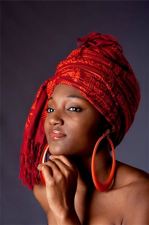 Beautiful African-American woman wearing a traditional tribal red orange head scarf and big orange hoop earrings, supporting her chin with hand, isolated. Stock Photo - Budget Royalty-Free & Subscription, Code: 400-04129583