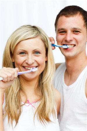 simsearch:400-04151135,k - Couple cleaning their teeth in bathroom smiling at the camera Stock Photo - Budget Royalty-Free & Subscription, Code: 400-04139559