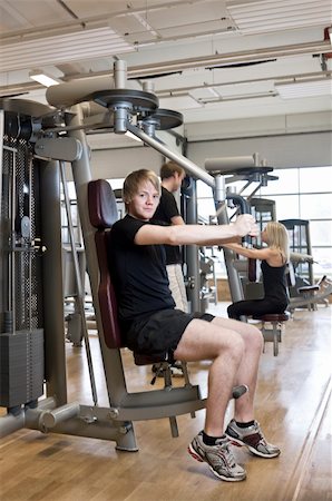 simsearch:400-04148009,k - Young man using an exercise machine at a health club with a girl and a boy in the background Photographie de stock - Aubaine LD & Abonnement, Code: 400-04147996