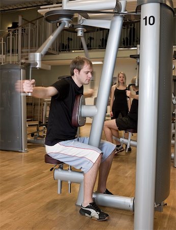 simsearch:400-04148009,k - Young man using an exercise machine at a health club with a girl and a boy in the background Photographie de stock - Aubaine LD & Abonnement, Code: 400-04147999
