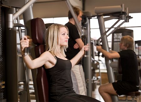 simsearch:400-04148009,k - Girl using an exercise machine at a health club with two men in the background Photographie de stock - Aubaine LD & Abonnement, Code: 400-04147991