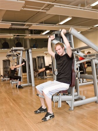 simsearch:400-04148009,k - Young man using an exercise machine at a health club with a girl and a boy in the background Photographie de stock - Aubaine LD & Abonnement, Code: 400-04148002