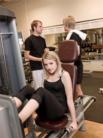 simsearch:400-04148009,k - Girl using an exercise machine at a health club with two men in the background Photographie de stock - Aubaine LD & Abonnement, Code: 400-04148022