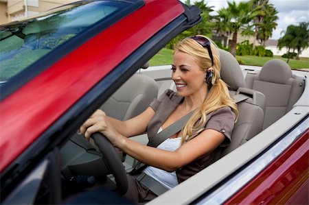 A beautiful young blond woman driving her convertible car and talking on her cell phone with a bluetooth headset Stock Photo - Budget Royalty-Free & Subscription, Code: 400-04148928