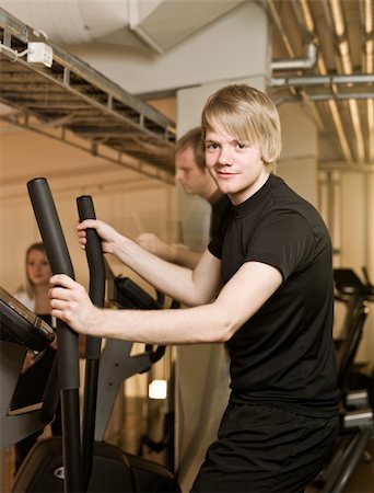 simsearch:400-04148009,k - Young man looking into the camera while using an exercise machine Photographie de stock - Aubaine LD & Abonnement, Code: 400-04149217