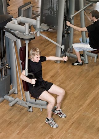 simsearch:400-04148009,k - Young man using an exercise machine at a gym. Photographie de stock - Aubaine LD & Abonnement, Code: 400-04149224