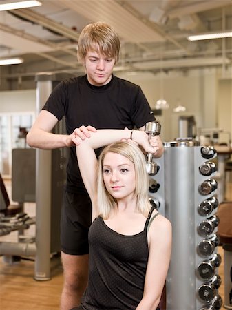 simsearch:400-04148009,k - Young man helping a girl lifting weights at a fitness center Photographie de stock - Aubaine LD & Abonnement, Code: 400-04149249