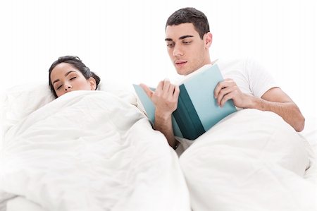 simsearch:400-04123175,k - Young handsome man reading book while a wife sleeping beside him in bed over white background Stock Photo - Budget Royalty-Free & Subscription, Code: 400-04165084