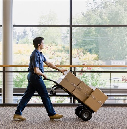 dolly - Young man using hand truck to move boxes.  Vertically framed shot. Stock Photo - Budget Royalty-Free & Subscription, Code: 400-04167547