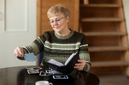 elder woman table - Senior woman viewing photo album in livingroom Photographie de stock - Aubaine LD & Abonnement, Code: 400-04169794