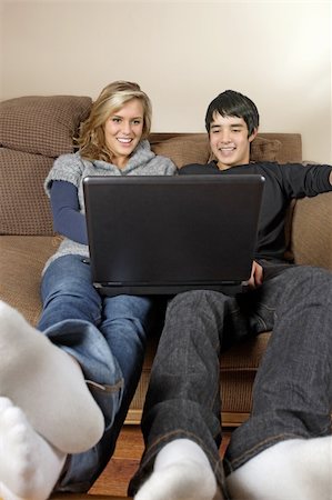 simsearch:400-05697169,k - Two happy teenagers, Caucasian female and Asian male, sitting on a couch surfing the internet. Stock Photo - Budget Royalty-Free & Subscription, Code: 400-04160591