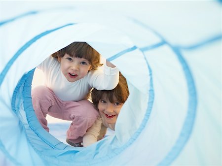 two 2-3 years old girls peeking from blue toy tunnel. Horizontal shape, Copy space Foto de stock - Super Valor sin royalties y Suscripción, Código: 400-04174898