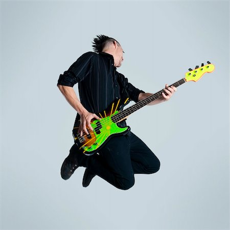 Awesome mohawk man jumps with his guitar in studio Stock Photo - Budget Royalty-Free & Subscription, Code: 400-04175905