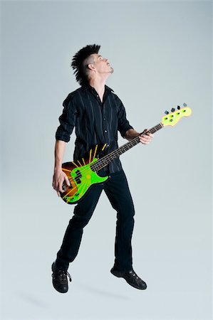 Awesome mohawk man jumps with his guitar in studio Stock Photo - Budget Royalty-Free & Subscription, Code: 400-04175901