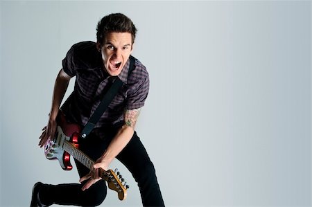 Awesome guitar player jumps with passion in studio Stock Photo - Budget Royalty-Free & Subscription, Code: 400-04175910