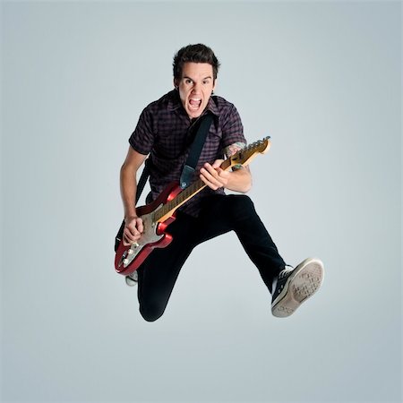 Awesome guitar player jumps with passion in studio Stock Photo - Budget Royalty-Free & Subscription, Code: 400-04175911